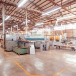 Vista ampla do interior de uma fábrica brasileira organizada, com máquinas industriais modernas.