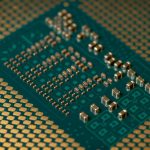 Close-up de um microprocessador e dos circuitos eletrônicos de uma placa, com componentes densamente interligados.