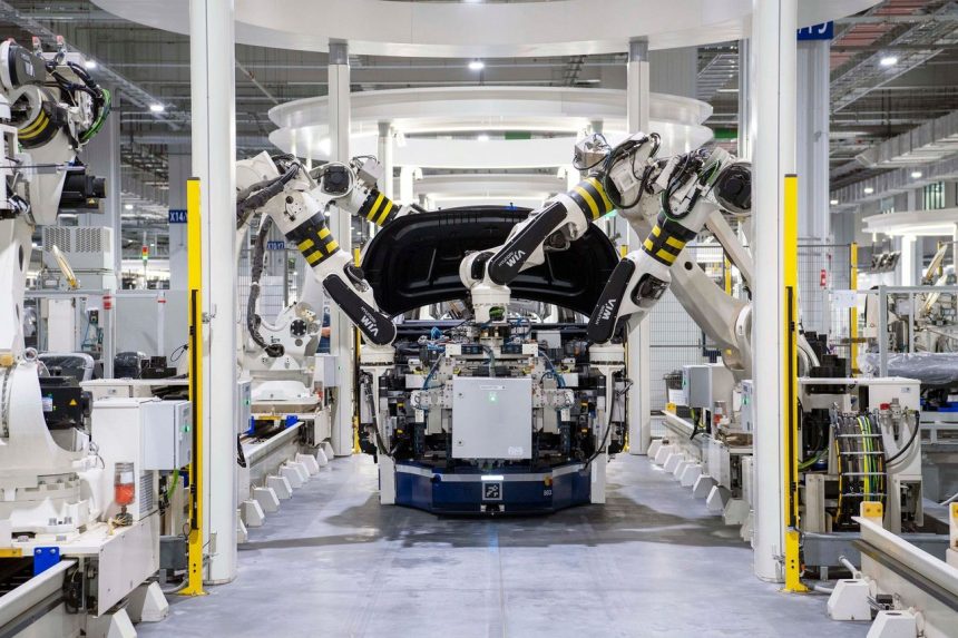 Robôs industriais trabalhando na montagem de um carro em uma fábrica automotiva moderna.