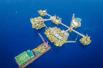Vista aérea de uma plataforma offshore de petróleo e gás em alto-mar.