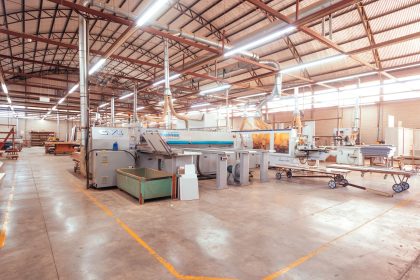 Vista ampla de uma fábrica brasileira organizada, com máquinas industriais em uma linha de produção.